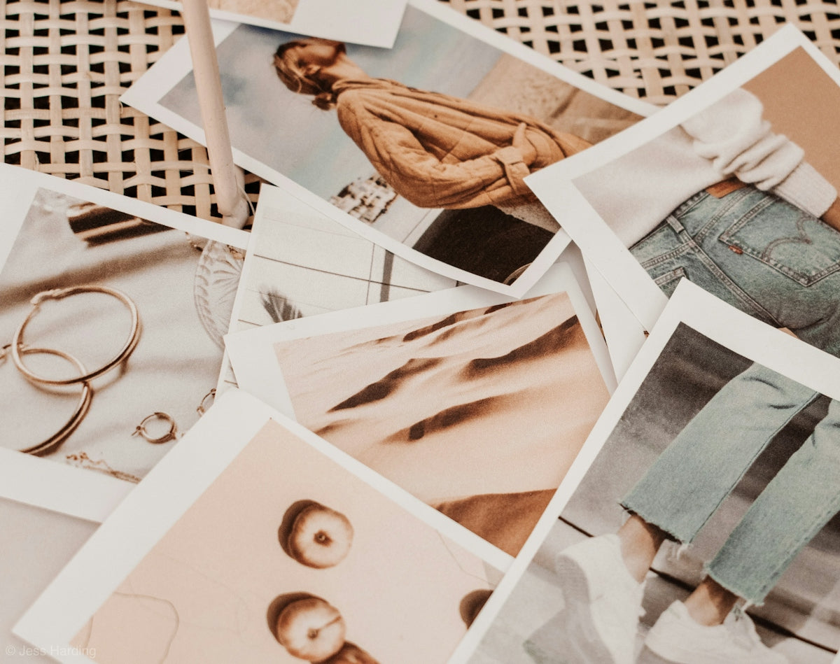 A collection of scattered photographs showing people, desert dunes, and jewelry on rattan